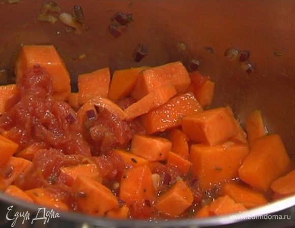 Выложить в кастрюлю с луком батат и тыкву, перемешать, добавить помидоры в собственном соку и еще раз все перемешать.