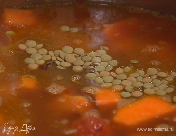 Всыпать чечевицу, залить все горячим бульоном и варить суп до готовности чечевицы.