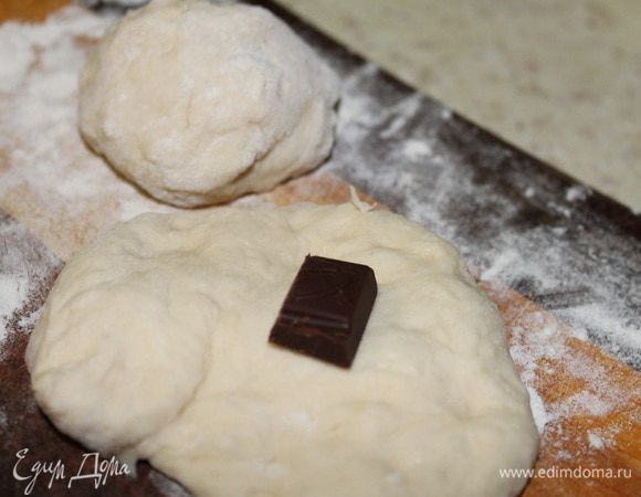 Отщипываем кусочек теста, расплющиваем его в ладошке, кладем кубик шоколада, хорошо защипываем края собирая их к центру, чтобы получился колобок. Масло выливаем в ковш и обжариваем пончики на среднем огне с двух сторон, до золотистого цвета.