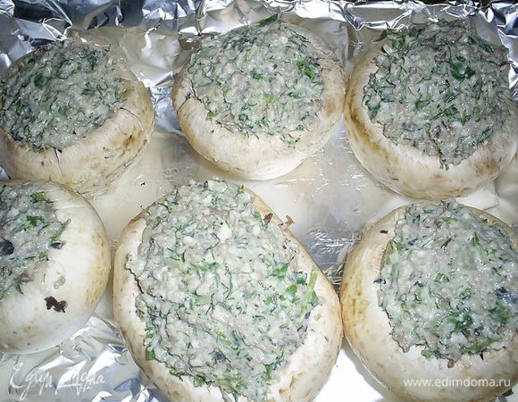 На растительном масле обжариваем мелко нарезанный лук, затем добавляем порезанные грибные ножки и извлеченную мякоть из шляпки. В последнюю очередь добавляем фарш и жарим до его готовности. Солим и приправляем по вкусу.
Еще для для начинки нам понадобится любой твердый сыр и зелень петрушки и укропа. Мне нравится, когда петрушки больше. Сыр натираем на крупной терке, половину сразу отложим, чтоб посыпать шампиньоны сверху. Добавляем мелко нарезанную зелень. Добавляем майонез и перемешиваем.
 Смешиваем все обе начинки. 
Полученной смесью начинить подготовленные шампиньоны.