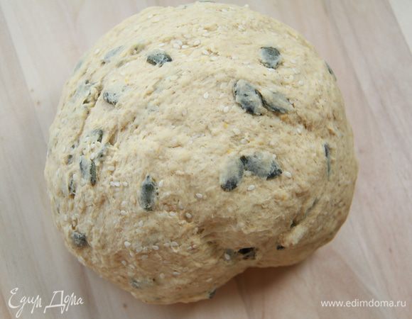 Через полчаса в тесто добавить кунжут (горсть отложить на украшение) и семена тыквы. Оставить на подъём на 1 час.