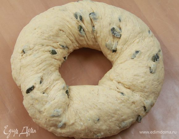 Скатать тесто в рулон длиной 45-50 см, сформировать кольцо, перегибая рулон жгутом (как будто выжимаете бельё), концы соединить и защипать. Выложить кольцо на антипригарный лист. Оставить кольцо на расстойку на 1 час, в пакете.