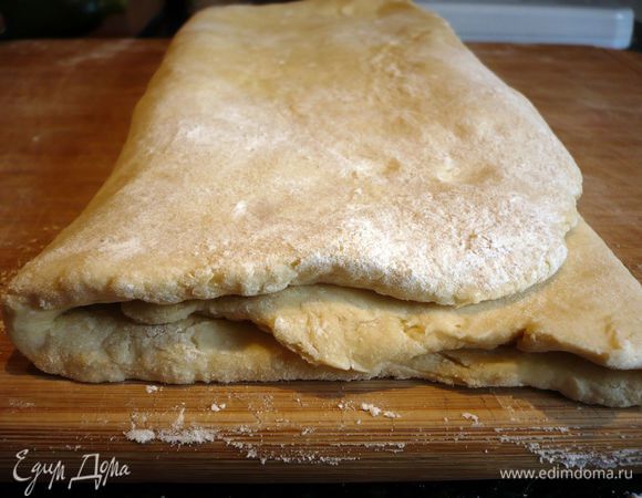 По удлиненной стороне пласта начинаем заворачивать тесто, зрительно поделив его на три равные части. Сначала с одной стороны, затем с другой так, чтобы левый край лег на правый.
Вот что у нас получилось.