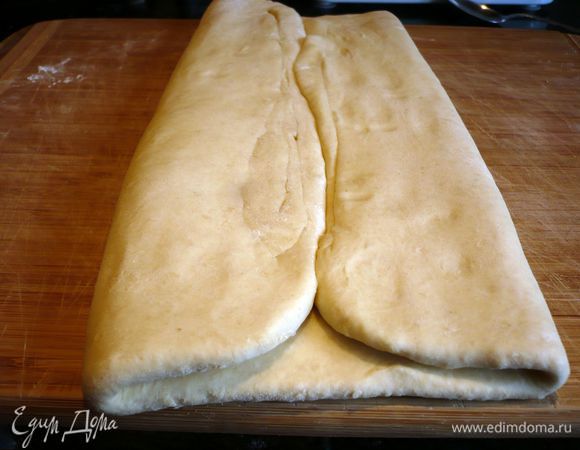 Достаем тесто. Раскатываем его на присыпанной мукой поверхности. Теперь зрительно делим тесто на четыре равные части. Сворачиваем левый и правый края к середине. 