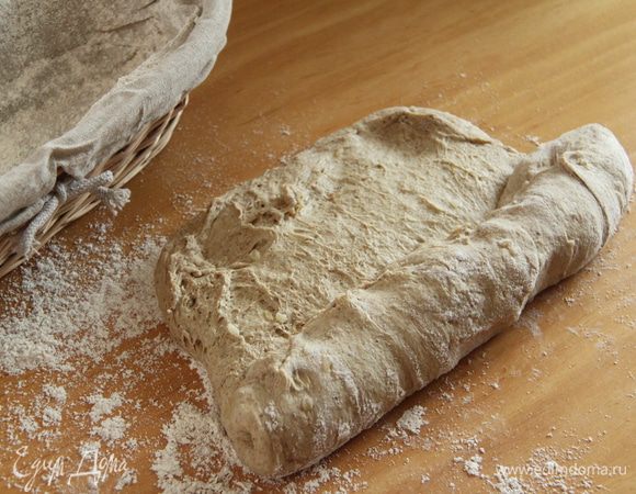 Рабочую поверхность припылить мукой, с помощью скребка выложить тесто и сформировать четырёхугольник. Завернуть плотно тесто рулетом.