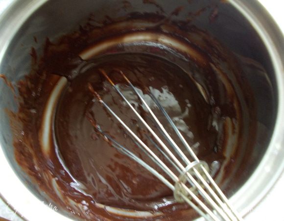 К немного остывшей шоколадной массе добавляем желтки и тщательно перемешиваем.