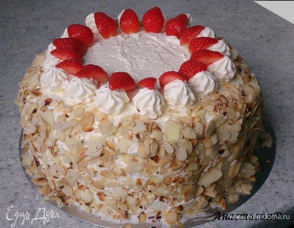 500 мл сливок крепко взбить с загустителем, 75 г сахара и 1 пакетиком ванильного сахара. 1/4 крема наполнить кондитерский мешок со звездообразной насадкой. Другой частью крема обмазать весь торт. Затем по бокам обсыпать миндалем. Украсить торт сливками и оставшейся клубникой.