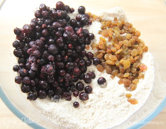 К мучной смеси добавить изюм и чёрную смородину (если замороженная, то не размораживать).