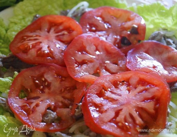 Помидоры нарезать острым ножом на тонкие кружочки и выложить поверх мяса.