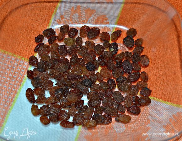Изюм промыть и залить тёплой водой на 10 мин. Затем воду слить и изюм обсушить с помощью бумажного полотенца.