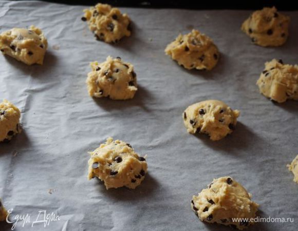 Добавляем шоколадные термостабильные капли, перемешиваем. С помощью столовой ложки выкладываем печенье на противень, застеленный пекарской бумагой.