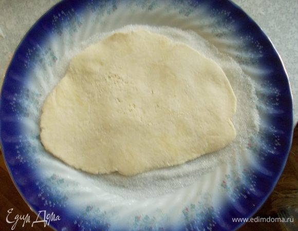 В плоскую тарелку насыпаем сахар. При необходимости досыпаем. Тесто раскатываем и кладем на сахар. Хорошо вдавливаем.