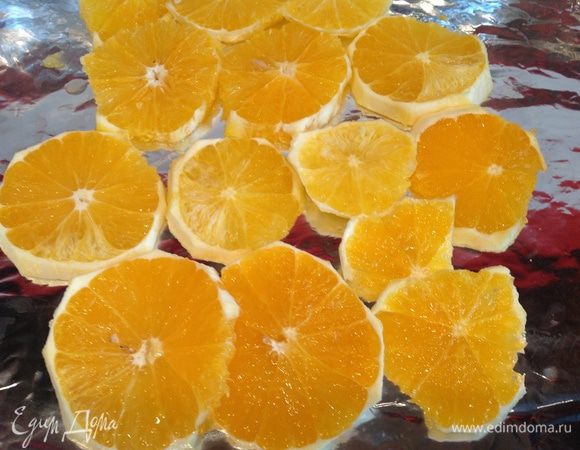 Очистите апельсины, нарежьте кружочками, выложите на противень застеленный фольгой.