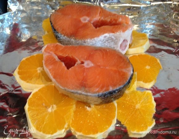 Выложите рыбу на апельсины, посолите.