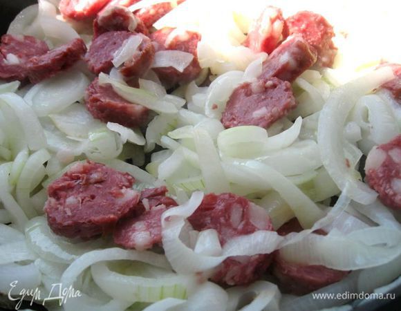 Обжарить лук на оливковом масле, через время добавить колбасу и тушить до выделения части жира из колбасы.  

