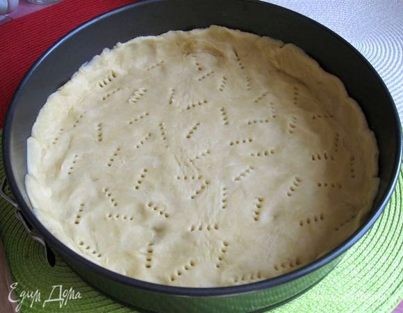  Взять тот круг теста, что побольше, положить в круглую форму, на дно которой положена бумага для выпечки, у теста должны быть небольшие бортики. Наколоть вилкой в некоторых местах. 

