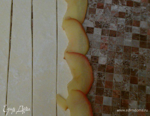 На полоску теста выложить 5-6 долек яблока, слегка внахлест. 
Дольки должны на одну треть выступать за верхний край теста.
Аккуратно скрутить полоску в трубочку.
Нижние края теста подвернуть вовнутрь.