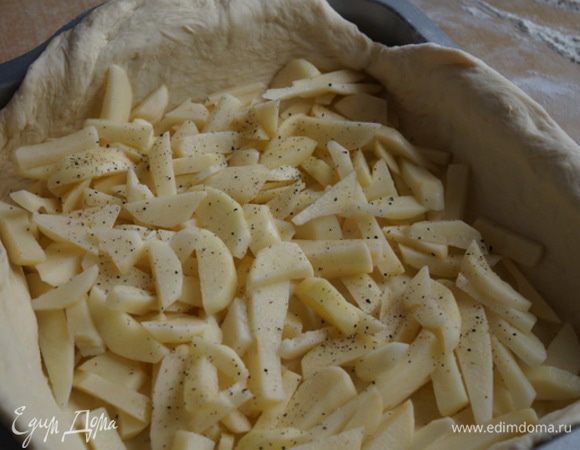 Начинаем формировать пирог. Раскатываем тесто, укладываем в форму для выпечки. Первым слоем начинки выкладываем сырой картофель,