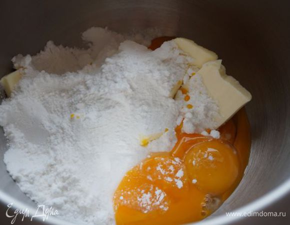 В это время приступим к работе с начинкой. Мягкое сливочное масло взбить с желтками и половиной сахарной пудры в пышную светлую массу.