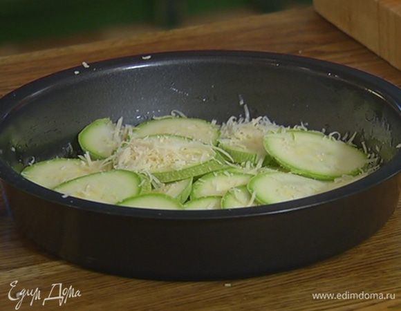 Небольшую форму для выпечки смазать оставшимся оливковым маслом, присыпать дно частью натертого сыра, выложить кружки кабачка (можно в форме цветка), немного посыпать сыром и посолить.