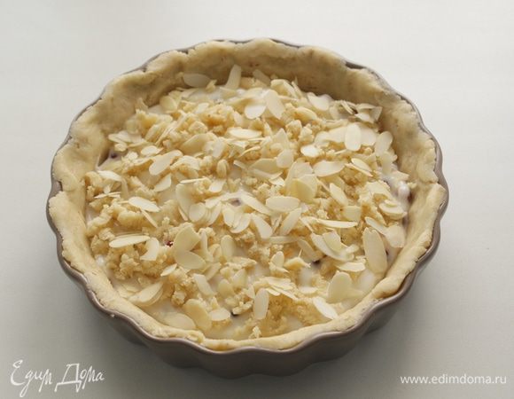 Достать оставшееся тесто из холодильника, раскрошить его поверх рикотты, можно дополнительно украсить миндальными лепестками и клюквой.