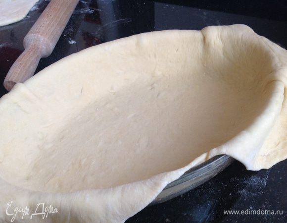 Аккуратно выложите, в смазанную оливковым маслом, форму и слегка разровняйте по дну и стенкам, оставив тесто свисать по краям.