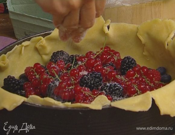 Выложить на тесто ягоды, немного присыпать их сахаром и загнуть края теста, накрыв им ягоды — середина должна остаться открытой.