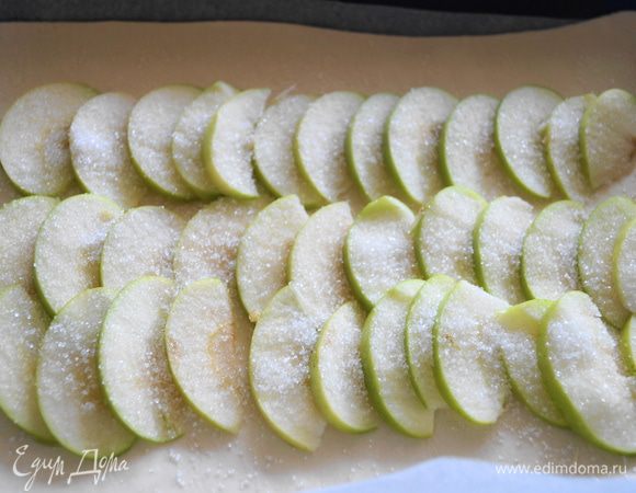 Яблоко нарезать тонкими пластинами, и выложить на пласт теста, присыпать немного сахаром.