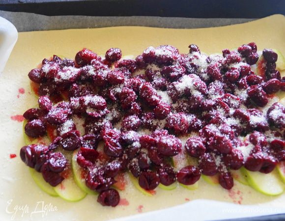 Размороженную вишню немного отжать от лишнего сока, присыпать сахаром по вкусу, сверху полить небольшим количеством меда. Края теста смазать яичным белком.