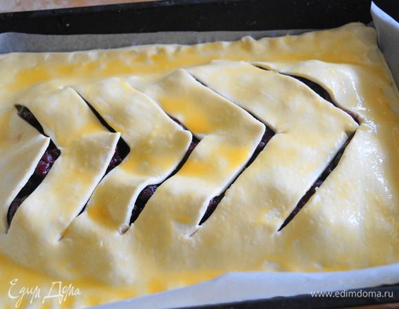 Развернуть пласт теста, и накрыть им верх пирога. Прижать края теста. Смазать пирог яичным желтком.