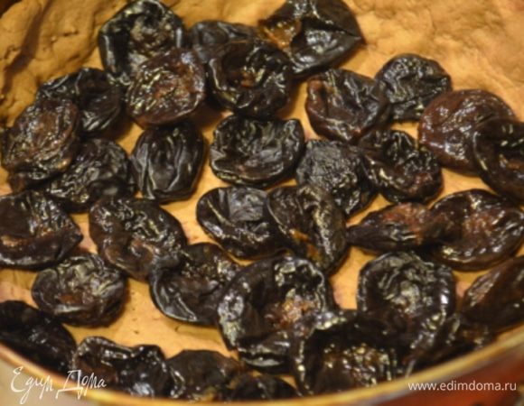 На испеченный корж выкладываем чернослив (при этом остатки жидкости с него надо слить).