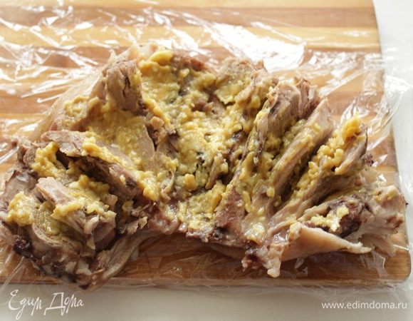 Укладываем рульку на пищевую пленку кожицей вниз. Покрываем рульку со стороны мяса  маринадом. 