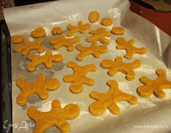 Спустя 2-3 часа достать шар из холодильника, слегка размять, раскатать на присыпанной мукой поверхности в пласт толщиной 5 мм. Формочками или трафаретом в виде человечков вырезать прянички, выложить их на противень, застеленный пергаментной бумагой.