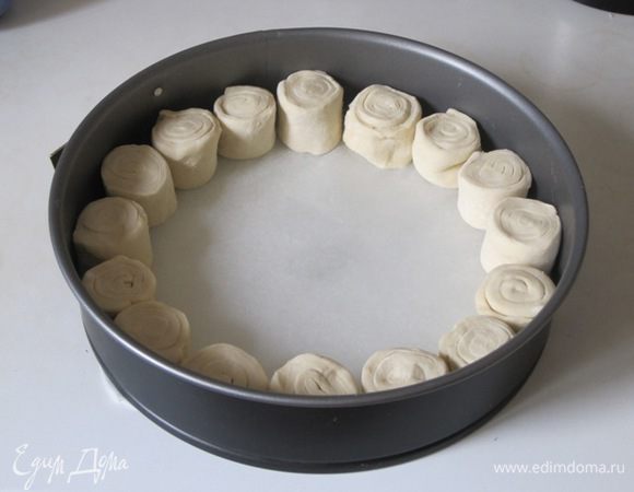 Дно круглой формы размером 24-26 см застелить бумагой для выпечки. Выложить кружки теста по кругу.