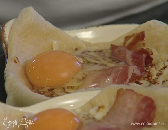 Разбить в каждую по 2 яйца, положить по нескольку кусочков бекона.