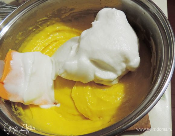 Теперь соединяем теплые белки с еще горячим кремом. Сначала добавляем примерно треть белков. Перемешиваем аккуратно лопаткой движениями снизу вверх от краев к центру.