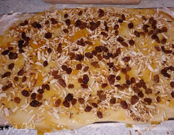 Тесто смазать конфитюром. Выложить также изюм и миндаль.