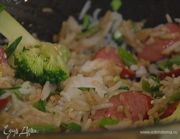 Добавить в сковороду колбаски, лук и кинзу (немного зелени оставить), посыпать кунжутным семенем, измельченным руками пеперончино, влить рисовый уксус и соевый соус, все перемешать.