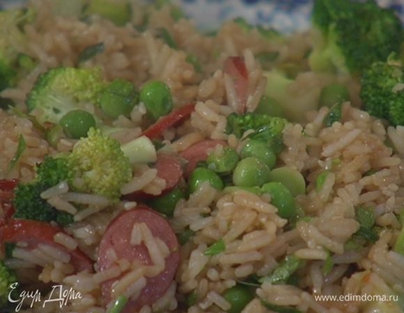 Выложить к рису с колбасками зеленый горошек и обжаривать 2–3 минуты.