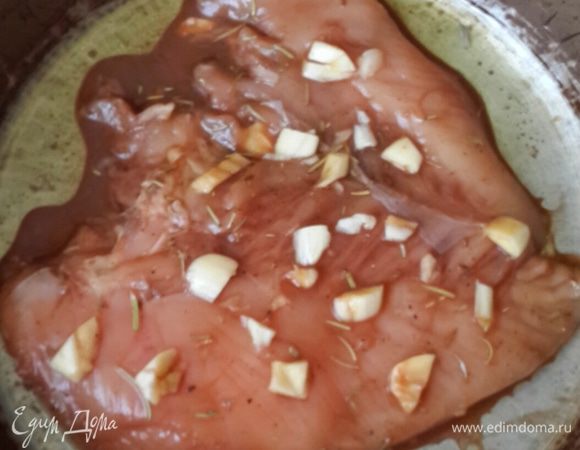 Выкладываем в форму для духовки мясо, обкладываем кусочками чеснока, поливаем маринадом. 