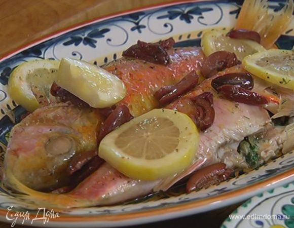 Готовую рыбу переложить на тарелку, сверху выложить кружки лимона и полить выделившимся при запекании соком.