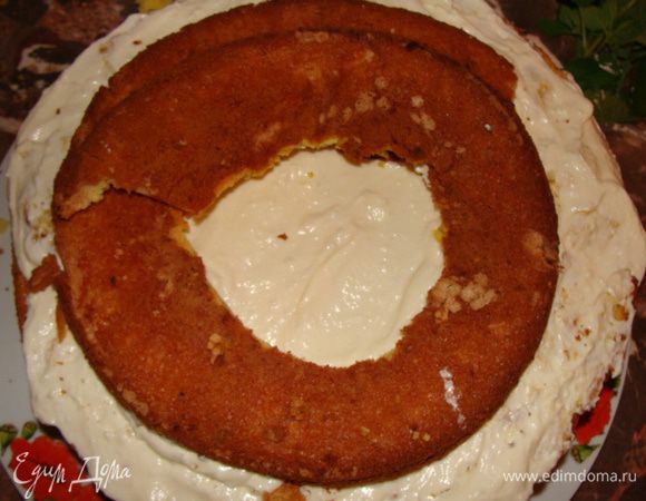 Сверху кладем слой крема, накрываем апельсиновым коржом. Снова покрываем творожным кремом. Далее из последнего апельсинового коржа вырезаем середину, а оставшийся с пустым отверстием, надрезаем и выкладываем, формируя спираль.