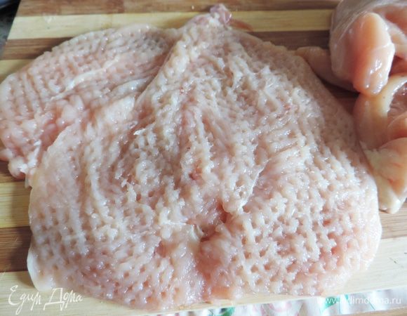 Теперь нам надо слегка отбить мясо. Удобно это сделать с помощью пищевой пленки. Застилаем разделочную доску пищевой пленкой, кладем подготовленное филе, накрываем пищевой пленкой и отбиваем его молотком.