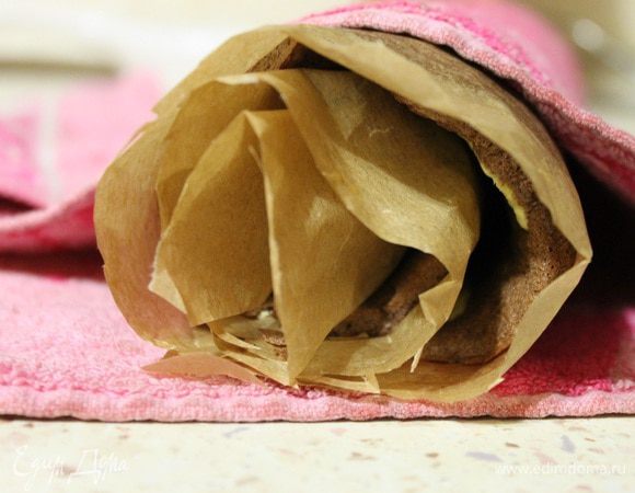 Бисквит у меня был готов через 13 минут, достаем из духовки, вместе с пергаментом перетаскиваем на стол и сворачиваем рулетом так, чтобы пергамент был сверху. Накрываем полотенцем и даем остыть.