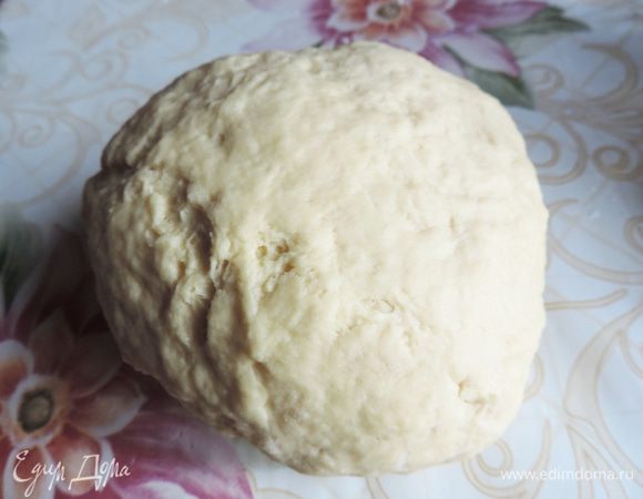 Первым делом займемся тестом. Яйцо слегка взбиваем вилкой или венчиком с солью и сахаром. Затем добавляем простоквашу. У меня она всегда домашняя и я стараюсь набирать ее из банки без сыворотки. Можно готовить и просто на сыворотке или на кефире, но я приспособилась именно так.
Перемешиваем яйцо с простоквашей и всыпаем половину муки, сверху высыпаем чайную ложку соды без верха. Перемешиваем ложкой до получения однородного теста, чтобы сода равномерно распределилась. Затем понемногу начинаем досыпать муку и вымешиваем тесто уже руками. Количество муки каждый раз может быть разным, потому что простокваша может быть разной густоты и размеры яйца тоже могут существенно отличаться. Нам надо добиться, чтобы тесто не липло к рукам, но в то же время было мягким.
Собираем тесто в шар и заворачиваем в пищевую пленку. Даем отдохнуть, пока займемся начинкой.