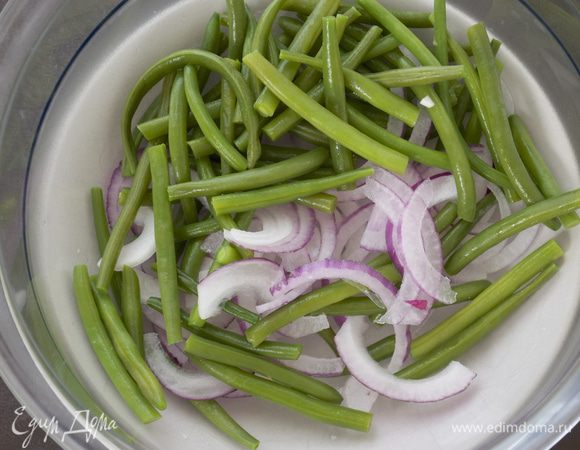 Разрезать стручки фасоли пополам. Нарезать тонко красную луковицу. В большой миске смешать фасоль и лук. 