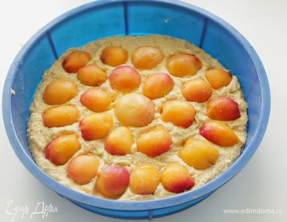 Выложить тесто в форму диаметром 22–24 см, сверху положить дольки абрикосов, слегка вдавив их в тесто.