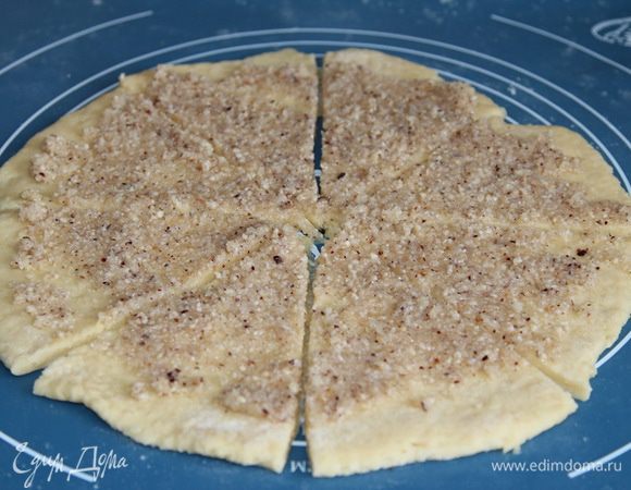 Хорошо подпыливаем мукой поверхность и раскатываем тесто в пласт толщиной около 5 мм, выкладываем половину начинки и равномерно распределяем по поверхности. Мокрым (чтобы тесто не тянулось за лезвием) острым ножом разрезаем на 8 частей.