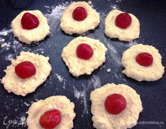 Из готового теста отщипываем кусочки и формируем небольшие лепешки.

В серединку каждой добавляем клубничку и скатываем шарики.