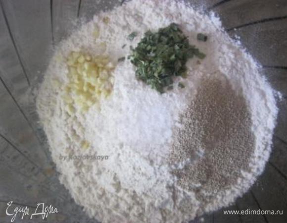 Просеять в миску примерно 3/4 муки.
Добавить сухие дрожжи, соль, сухой лук ( приправа сухая), и пропущенный через пресс чеснок.
Перемешать.